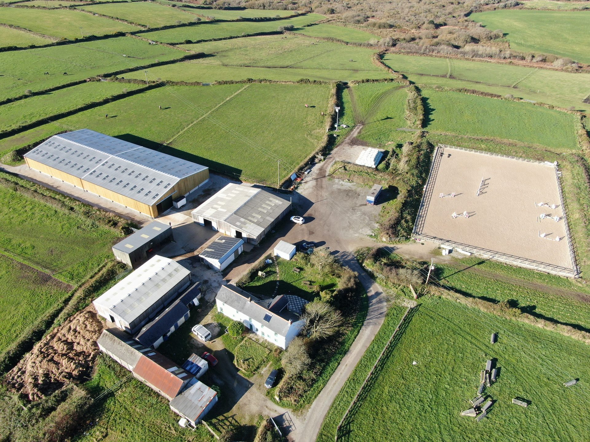 Aerial view of the Racehorse Relief farm in Cornwall — indoor arena, outdoor school, stables and surrounding fields